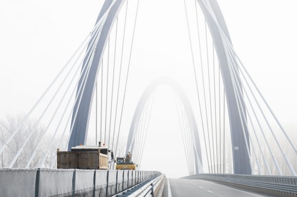 Munkagépek haladnak át angolosan az M44-es új Tisza-hídján 2021. december 15-én
