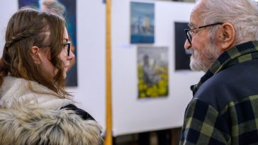 Mihály Martina és Lóránt János Demeter. A háttérben a fiatal festő alkotásai.
