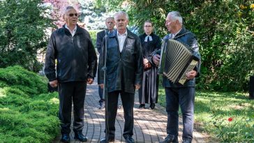 A Csabacsűdi Hagyományőrző Népdalkör és Citera Zenekar tagjai, Lipták András, Simon György és Major József katonadalokat adtak elő. A háttérben Molnár József polgármester és Magyar-Paulik Enikő evangélikus lelkész áll.