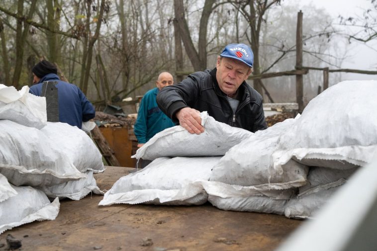 Molnár József polgármester segít a barnakőszén lepakolásában 2025. november 14-én.