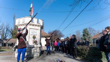 A Békés Megyei Károlyi-huszár és Honvéd Hagyományőrző és Kulturális Egyesület két tagja sortüzet lő az ünnep tiszteletére Csabacsűdön 2026. március 15-én.